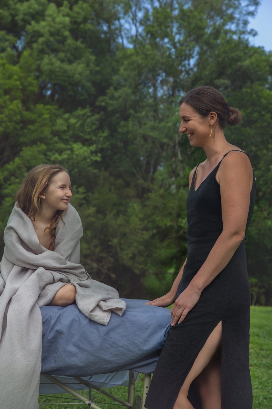 Katelyn with a child wrapped in a blanket after a session outdoors